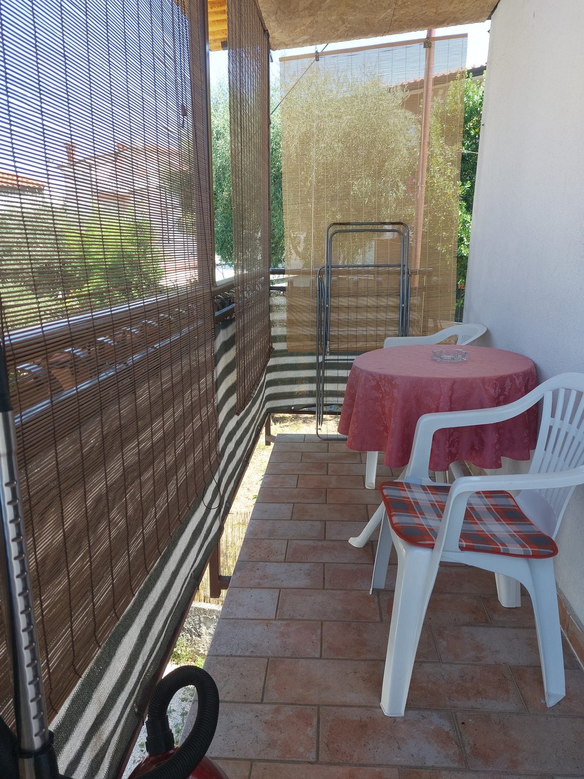 Natkriveni balkon sa zaštitom od sunca, stolom i stolicama