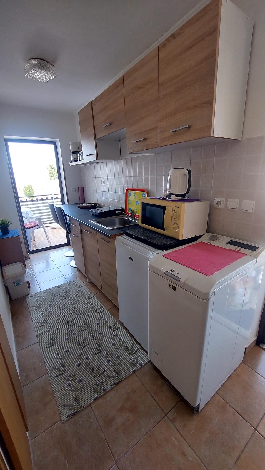 Kuhinjski kutak s perilicom rublja, hladnjakom i izlazom na balkon